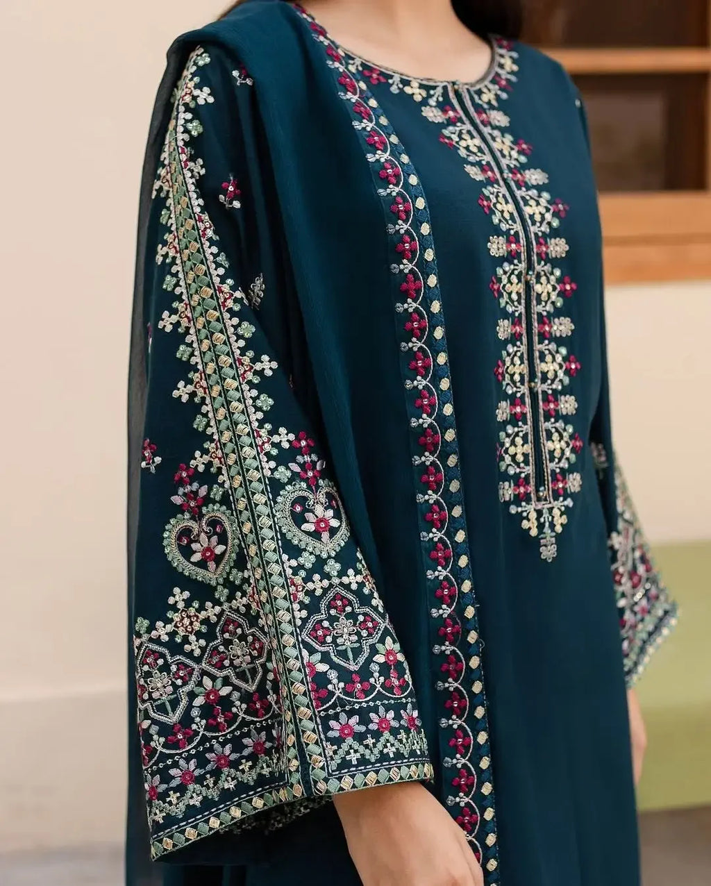 Close-up of dark teal embroidered kurta with intricate floral and geometric patterns on sleeves and front
